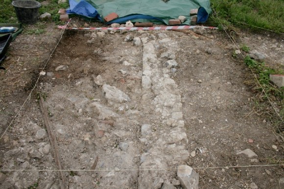 View looking S towards front of house (under tarpaulin) from garden/farmyard wall
