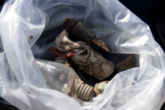 Limb of ceramic figurine, pen nib, light bulb, and piece of red plastic