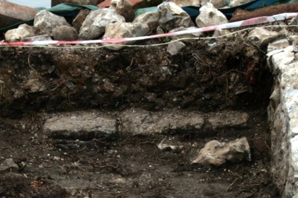 Row of stones about 30cm N of front of house
