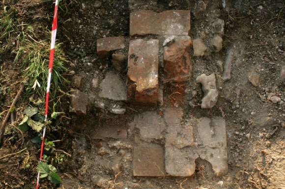 Looking W from door of 'woodshed' at brick quoin of junction with kitchen/scullery