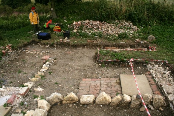 Looking E from garden/farmyard wall across area to front of house, including unexcavated area over possible water tank