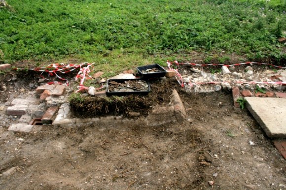 Looking S at concrete drain/gully in front of house between front door and woodstore