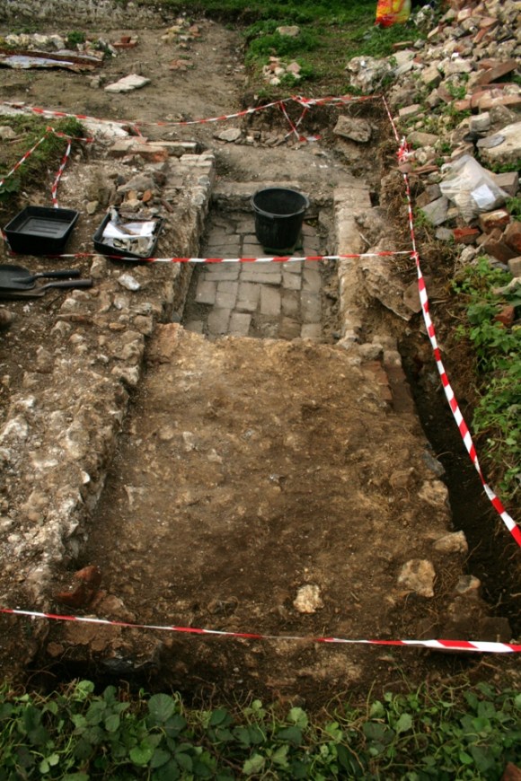 Looking N at concrete platform E of cottage (kitchen/scullery) wall, S of 'woodstore'