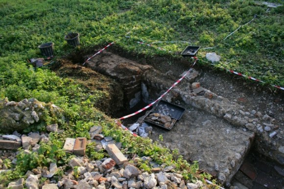 Looking SW from rubble mound at E side of cottage showing the base of the scullery copper, the internal house dividing wall, and the projecting base of the chimney of 19thc kitchen