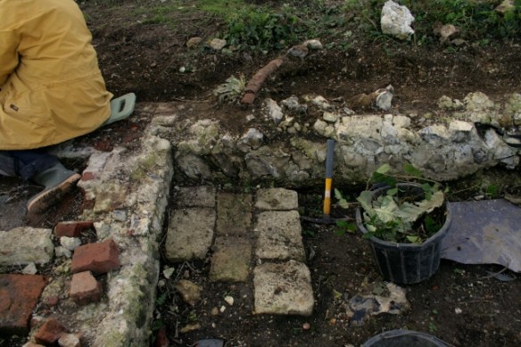 Looking W at water pipe over garden/farmyard wall a short distance in front of cottage