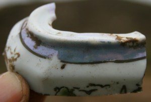 A shard of a decorative ceramic object with a narrow slot in the top; 13th December 2013.